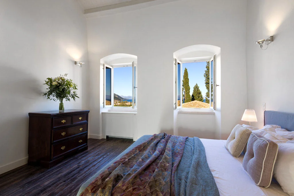 Bedroom with two windows showing sea and mountain views