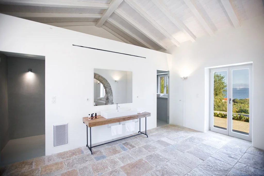 Shower area in bedroom with large sink and door leading to outsidee with sea and mountain views
