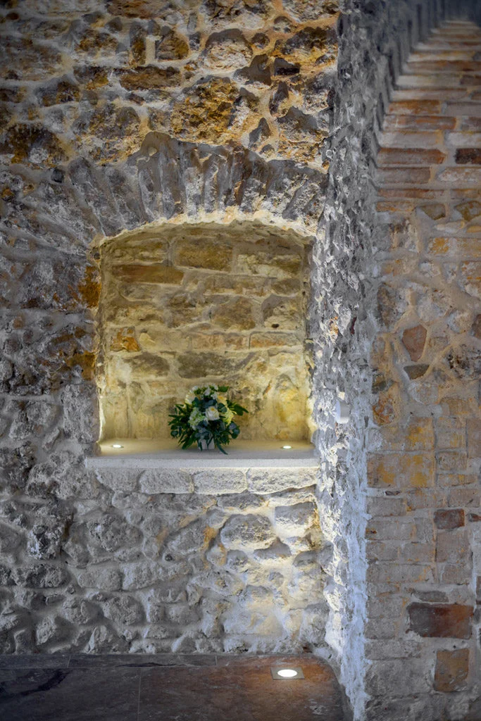 Feature in stone wall with flowers on shelf