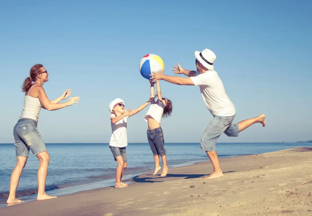 A family playing with a beach ball besign the sea.