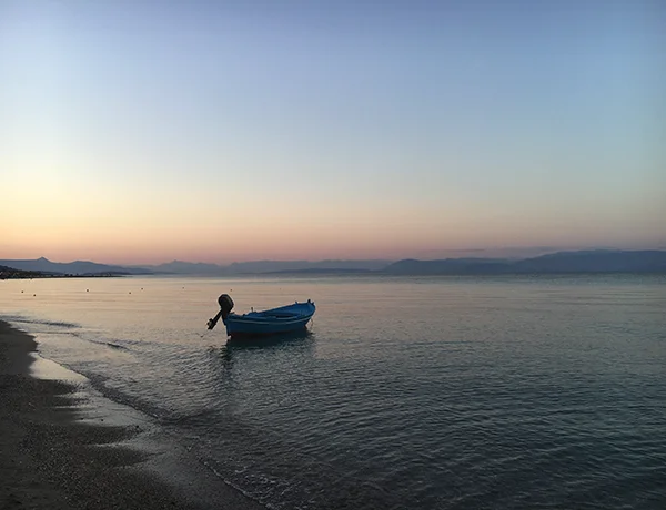 A small boat on the shore with mountains in the distance
