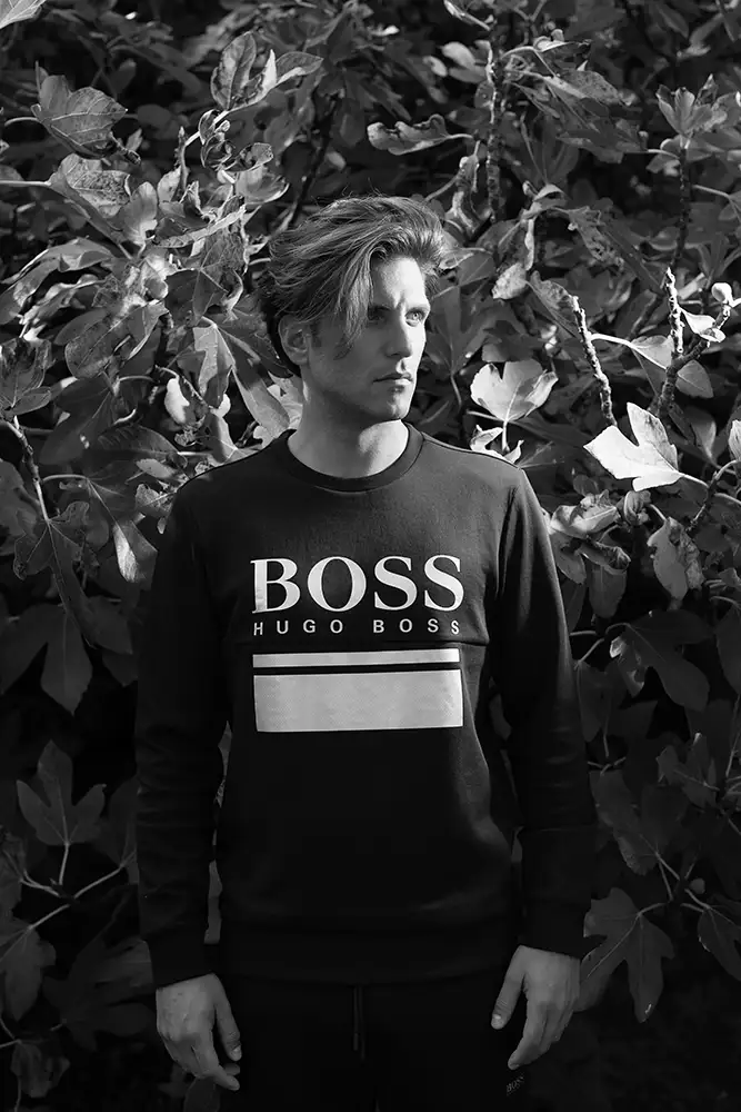 Model wearing a Hugo Boss top with shrubby backdrop.