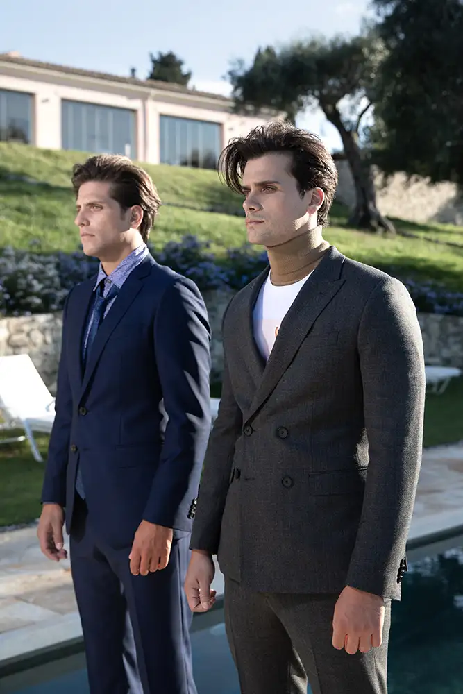 Models wearing suits standing on the edge of the Infinity Pool in the garden of The Courti Estate.