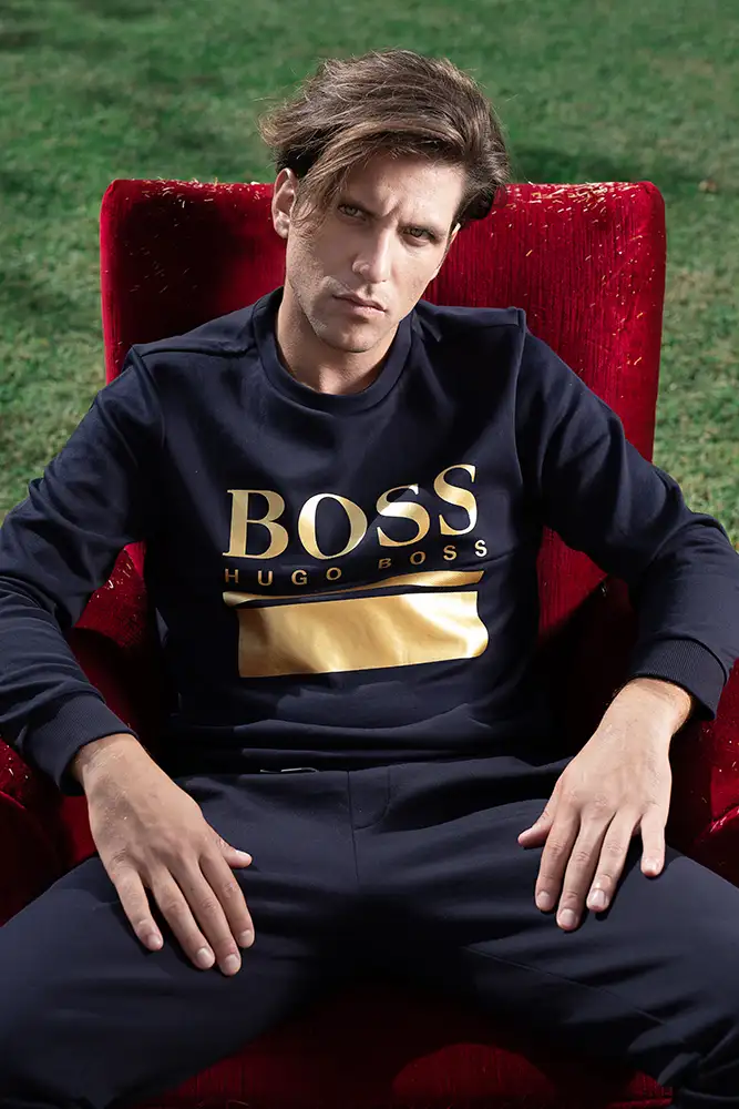 Model sitting in a red chair in the garden wearing an Hugo Boss top.