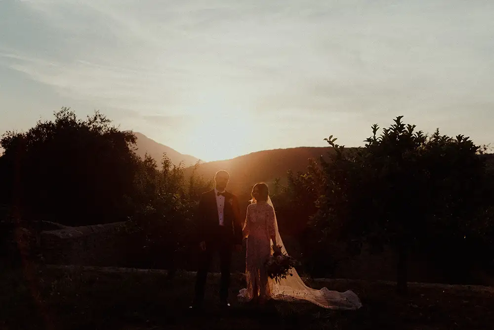 Bride and groom holding hand in the garden at sunset.