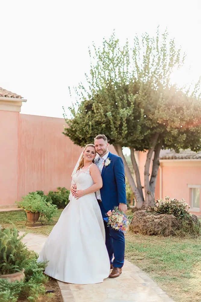 Bride and groom in the garden with olive trees and standing on garden path.