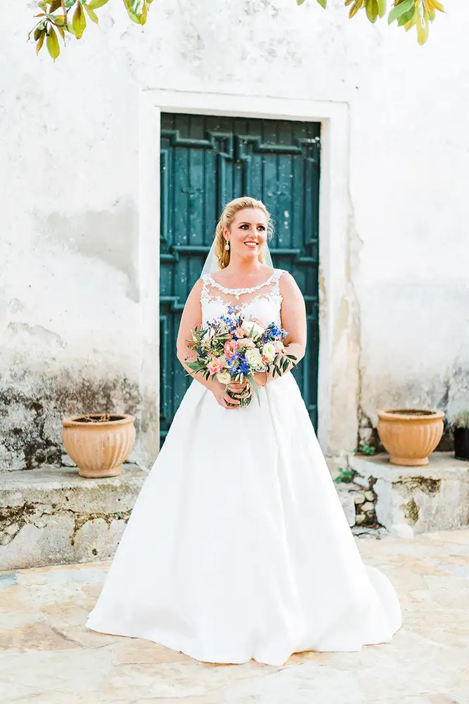 Bride holding bouquet with white walls and green door as a backdrop.