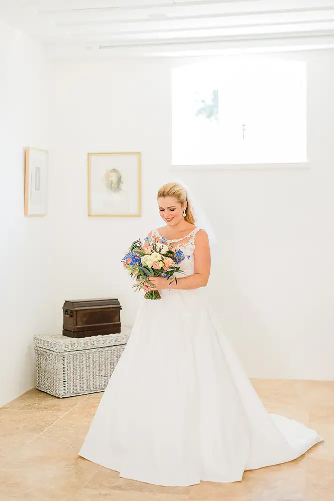 Bride in bedroom holding a bouquet.