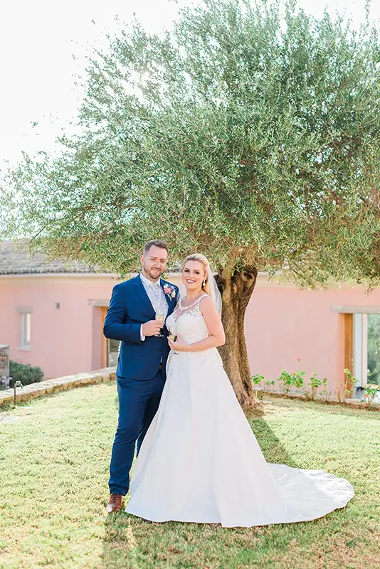 Bride and groom in the garden with an olive tree as a background.