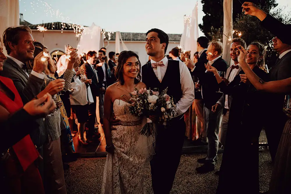 Bride and groom walking inbetween guests holding sparklers.