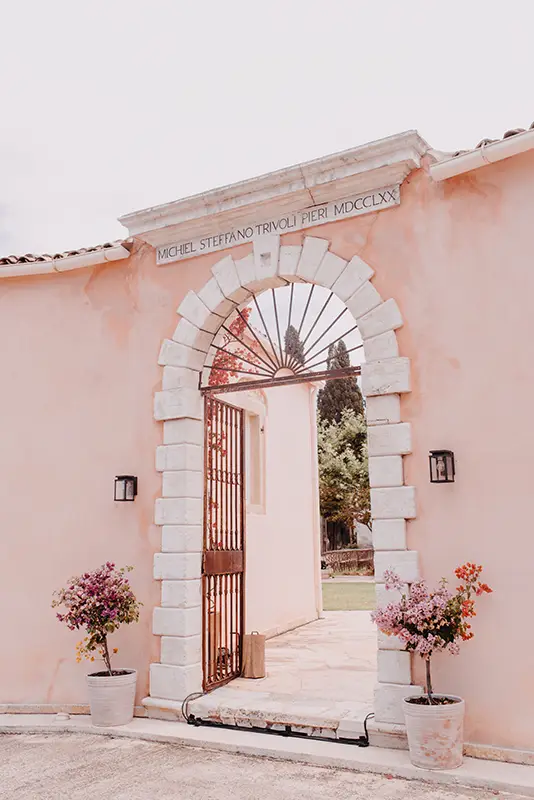 Iron gate entrance of The Courti Estate, Corfu with pink walls