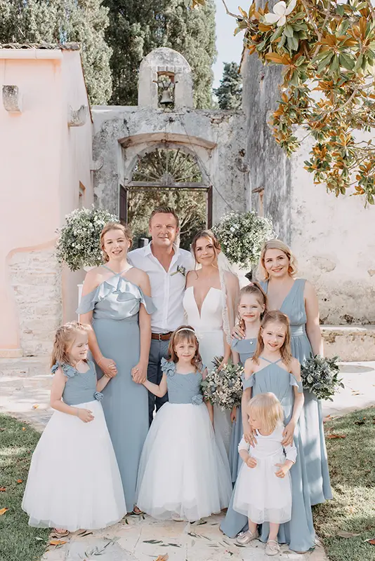 Bride and groom with bridesmaids and flower girls standing in front of iron gate