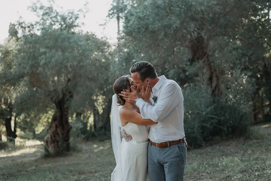Bride and groom kissing with olive trees in the background
