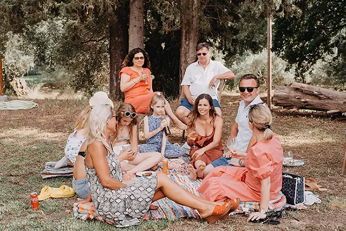 Wedding guests sitting down outside on picnic blankets drinking