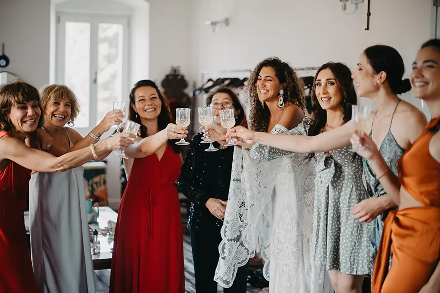 Bride with girl friends rasing a toast before the ceremony in the bedroom