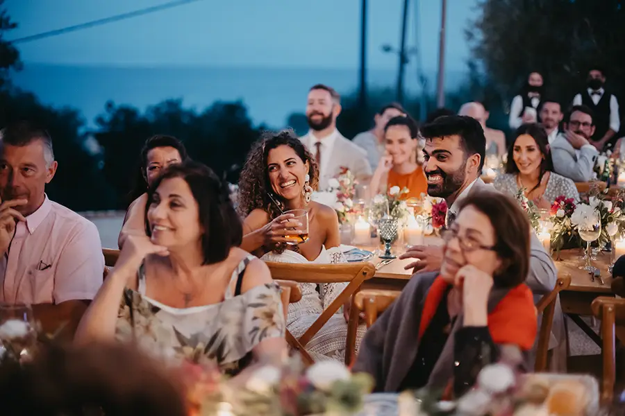 Bride and groom sitting down with other guests on table during reception