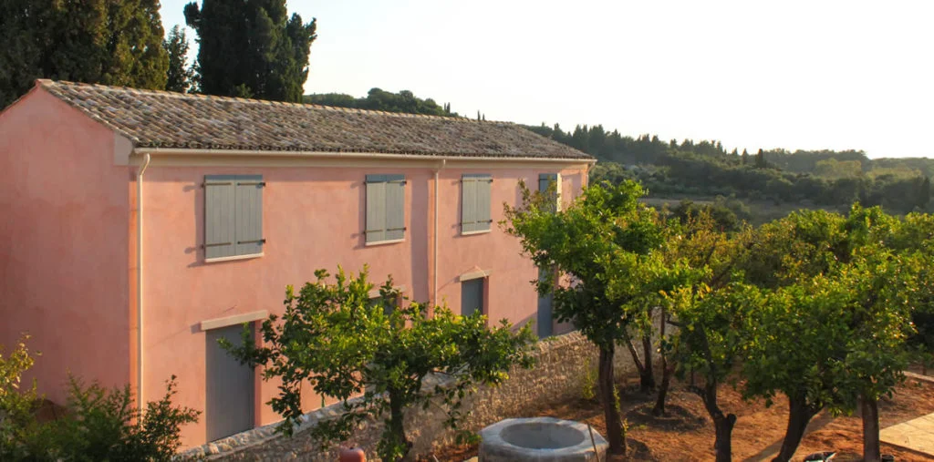 Evening sunshine on a Courti Estate building with olive trees in the garden